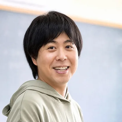 黒板の前で笑顔の石本大貴